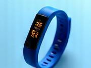 Overhead view of a vibrant blue fitness tracker band with a glowing screen.